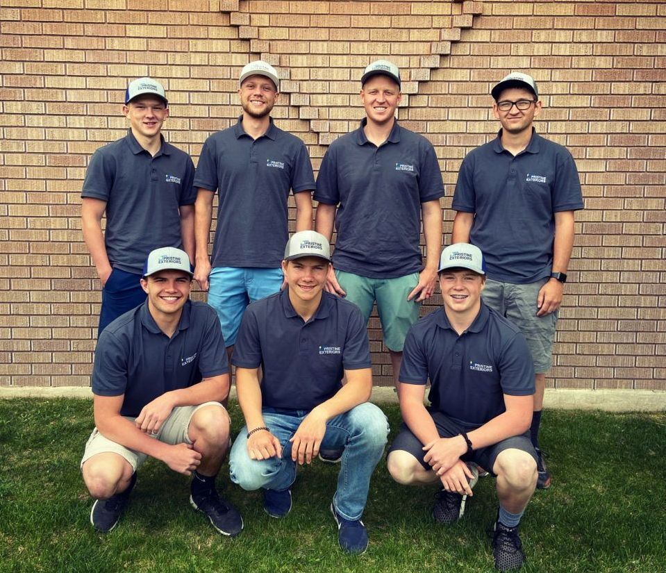 A group of young men are posing for a picture in front of a brick wall.