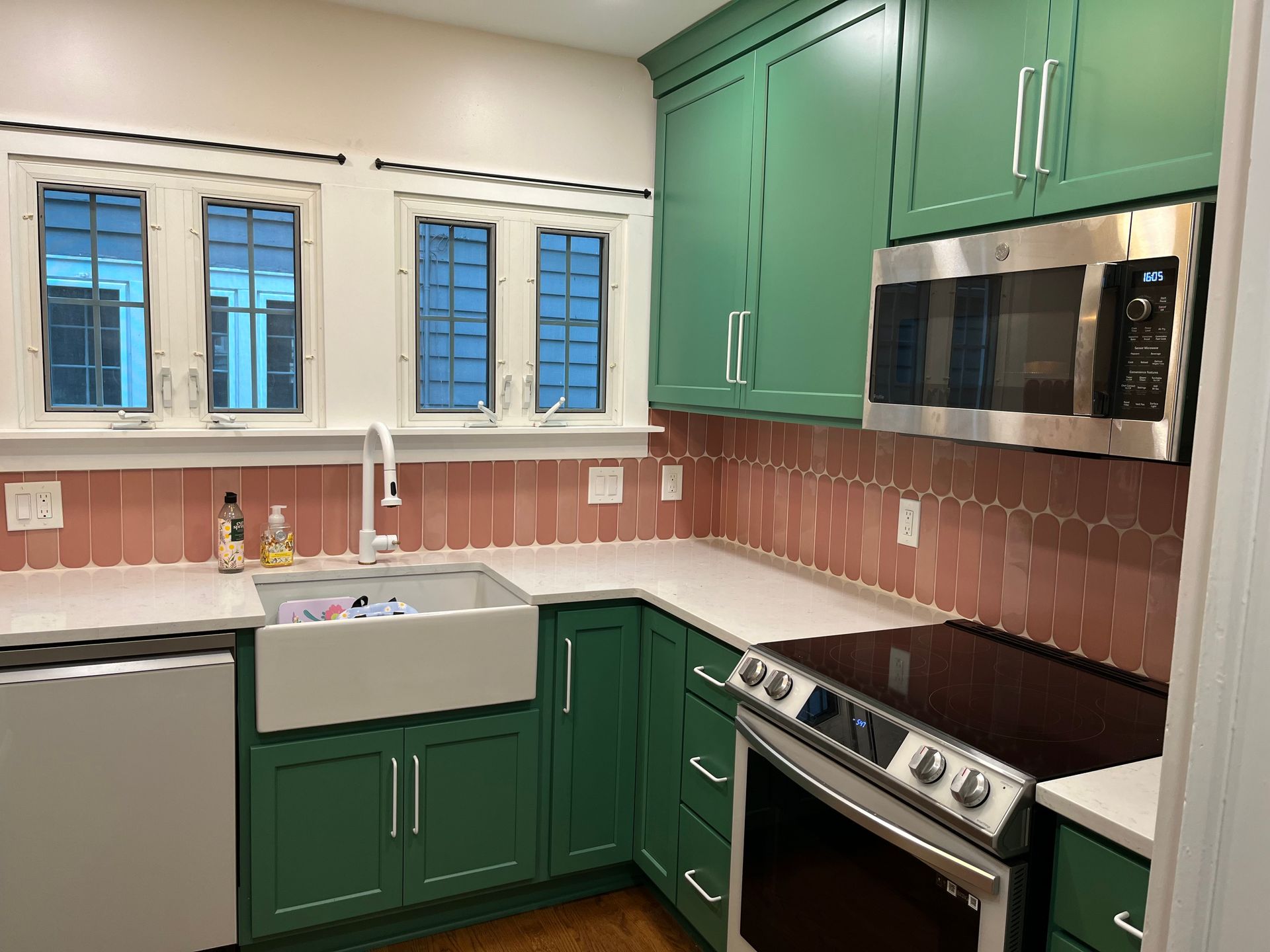 A kitchen with green cabinets and stainless steel appliances