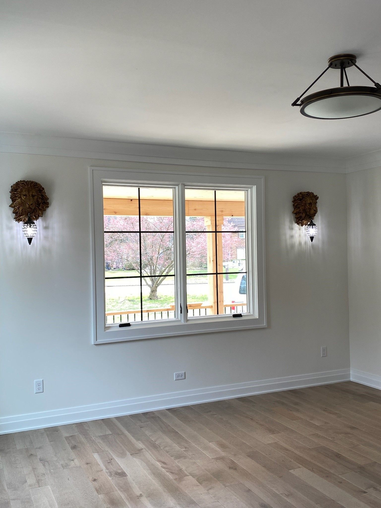 Interior room with a window, two sconces, and a wood floor.