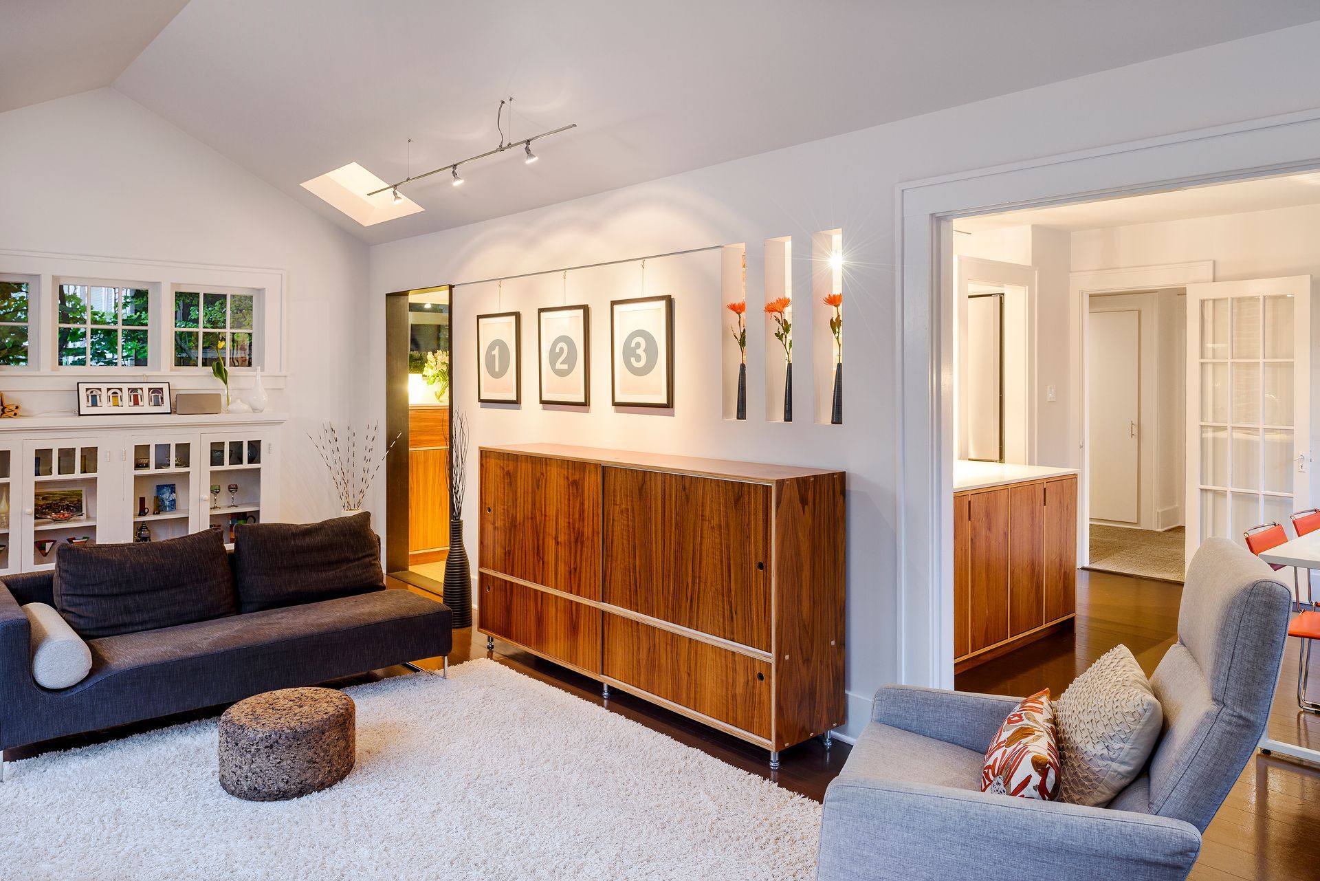 Living room with gray sofa, wood cabinet, and white walls.