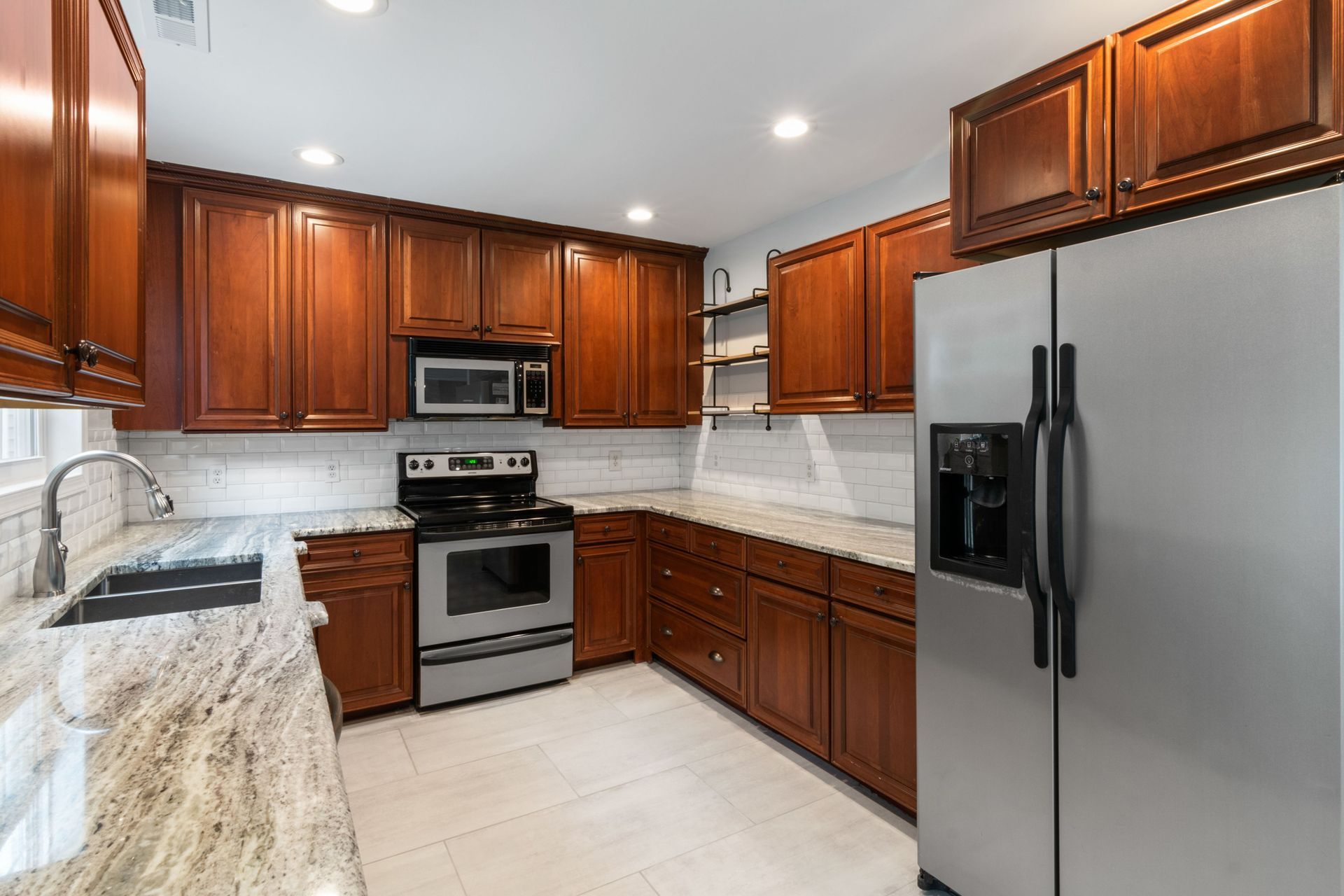 Modern kitchen with wood cabinets, stainless steel appliances, and light tile flooring