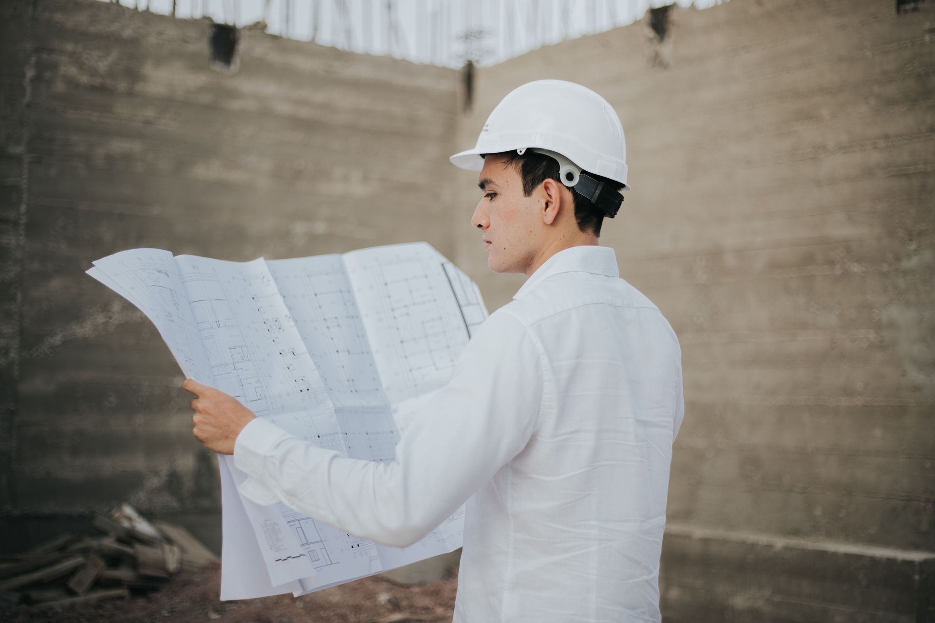Construction worker in white hard hat reviewing blueprints at a building site