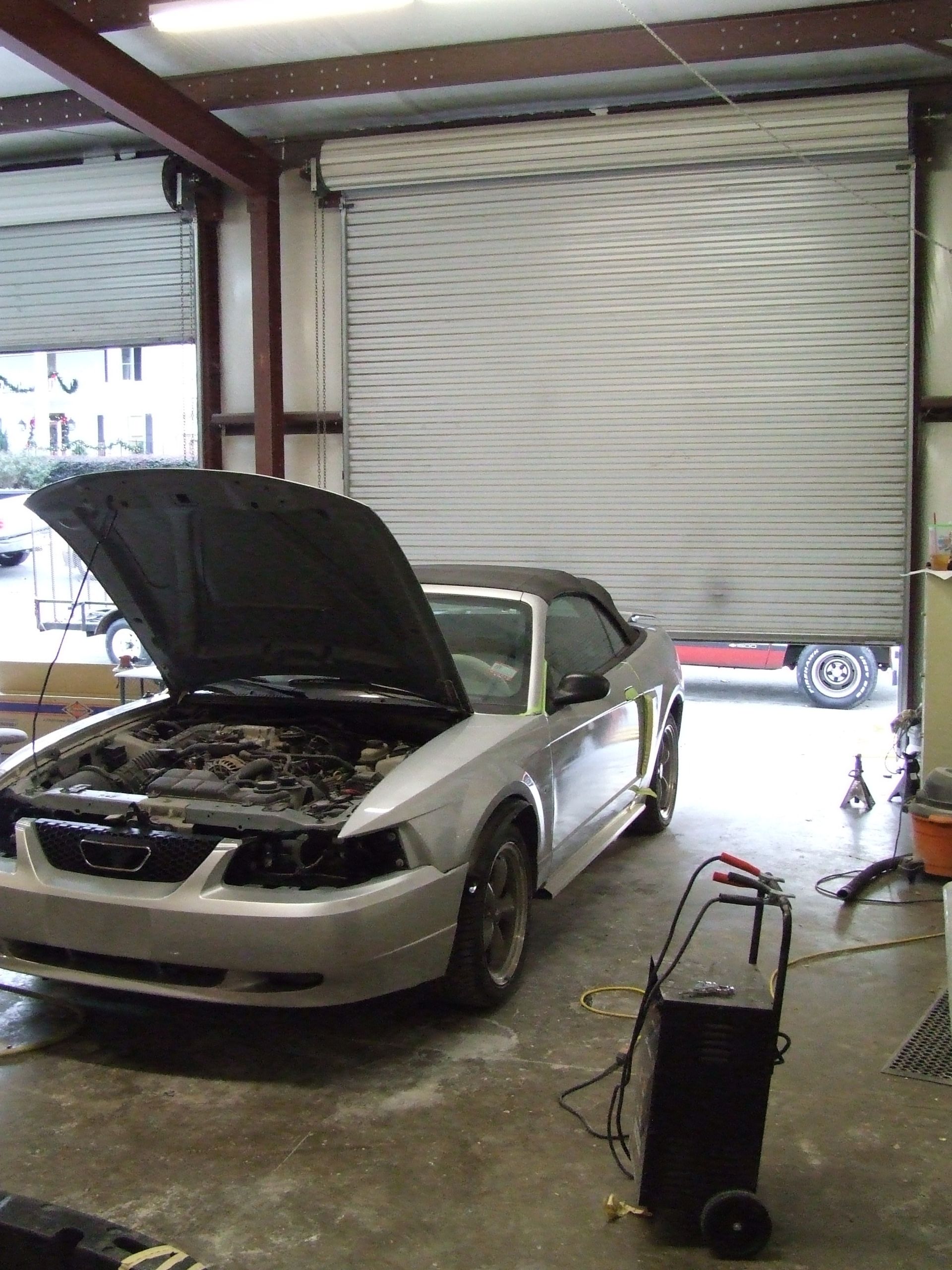 a car with the hood up is parked in a garage
