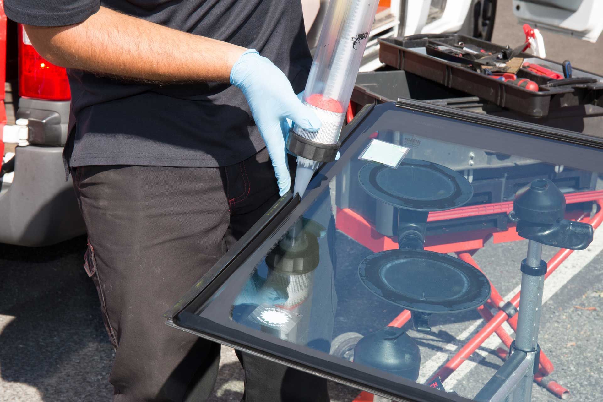 a man wearing blue gloves is working on a car windshield .