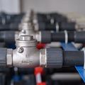 Two red industrial valves on a silver pipe against a concrete wall in a utility room