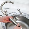 Kitchen sink with chrome faucet under a window and tiled backsplash