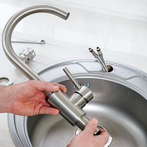 Kitchen sink with chrome faucet under a window and tiled backsplash
