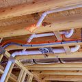 Hands using a red pipe wrench to fix plumbing under a sink