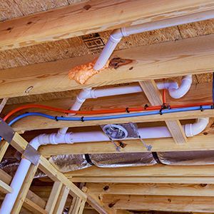 Hands using a red pipe wrench to fix plumbing under a sink