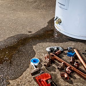 Three wall-mounted tankless water heaters with exposed copper piping on a dark exterior wall.
