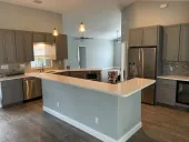 Modern kitchen with gray cabinets, white countertops, stainless steel appliances, and a breakfast bar.