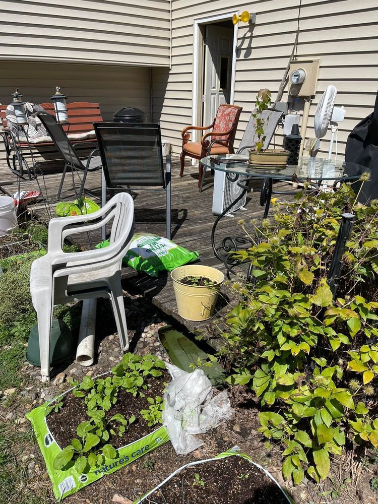 Backyard patio with chairs, table, potted plants, and gardening supplies.