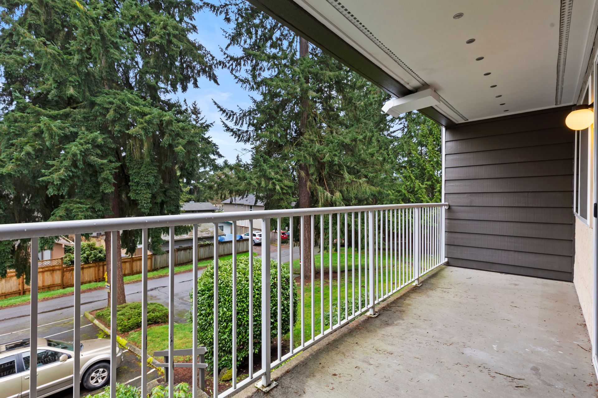a balcony with a metal railing overlooking a street and trees