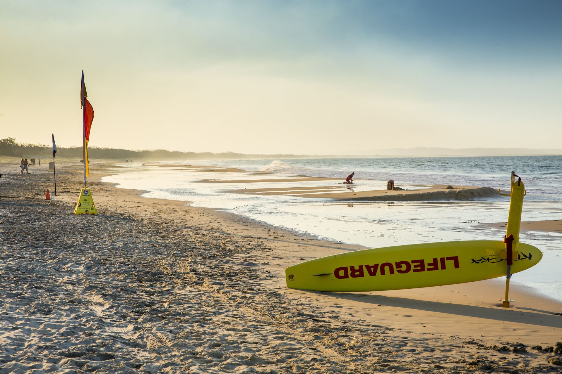 Beach at Sunrise With Surf Rescue Flags and a Yellow Rescue Board — Auto Maniac in Port Douglas, QLD