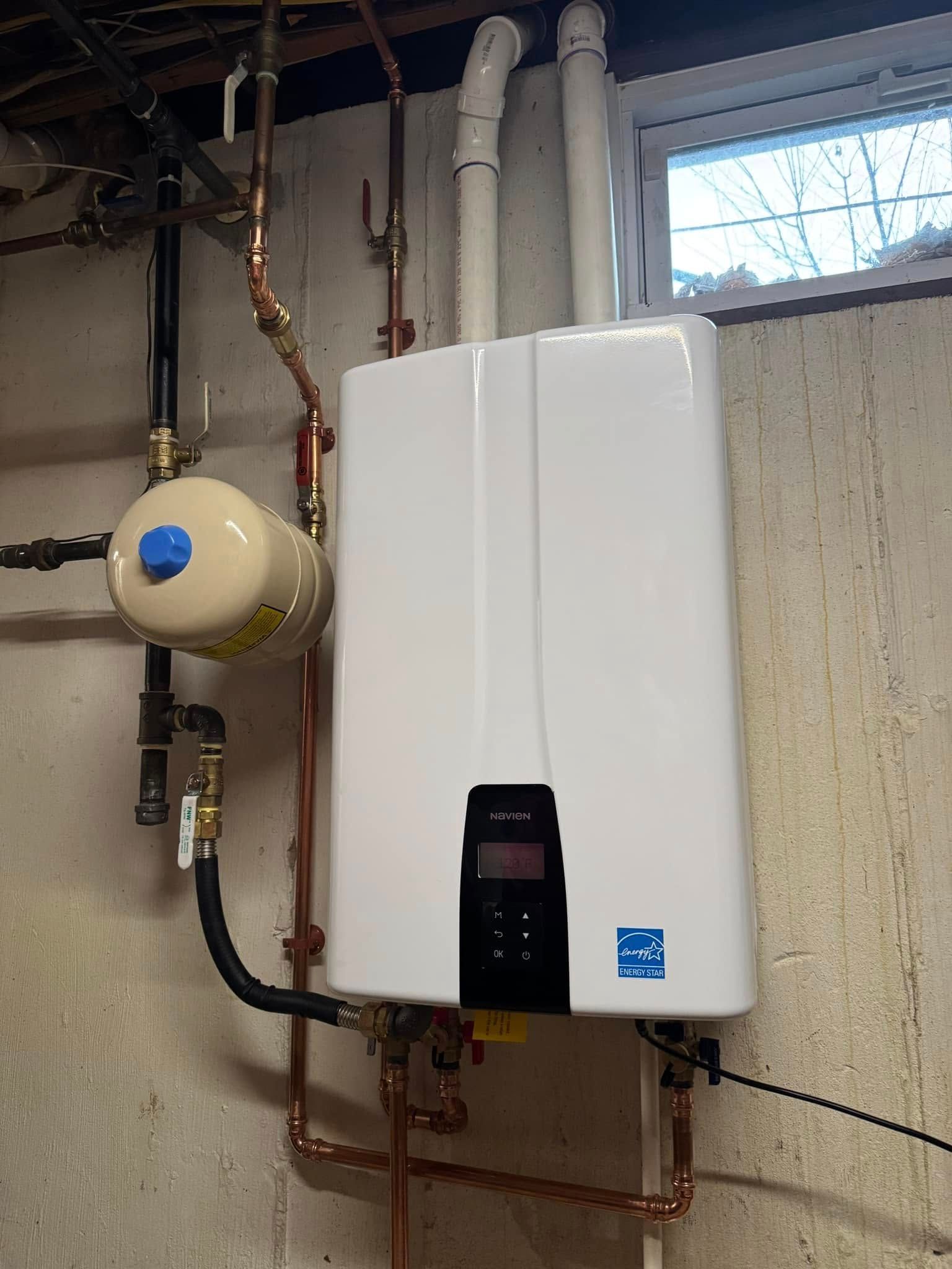 White wall-mounted boiler with copper pipes and a beige gas meter in a basement utility room.