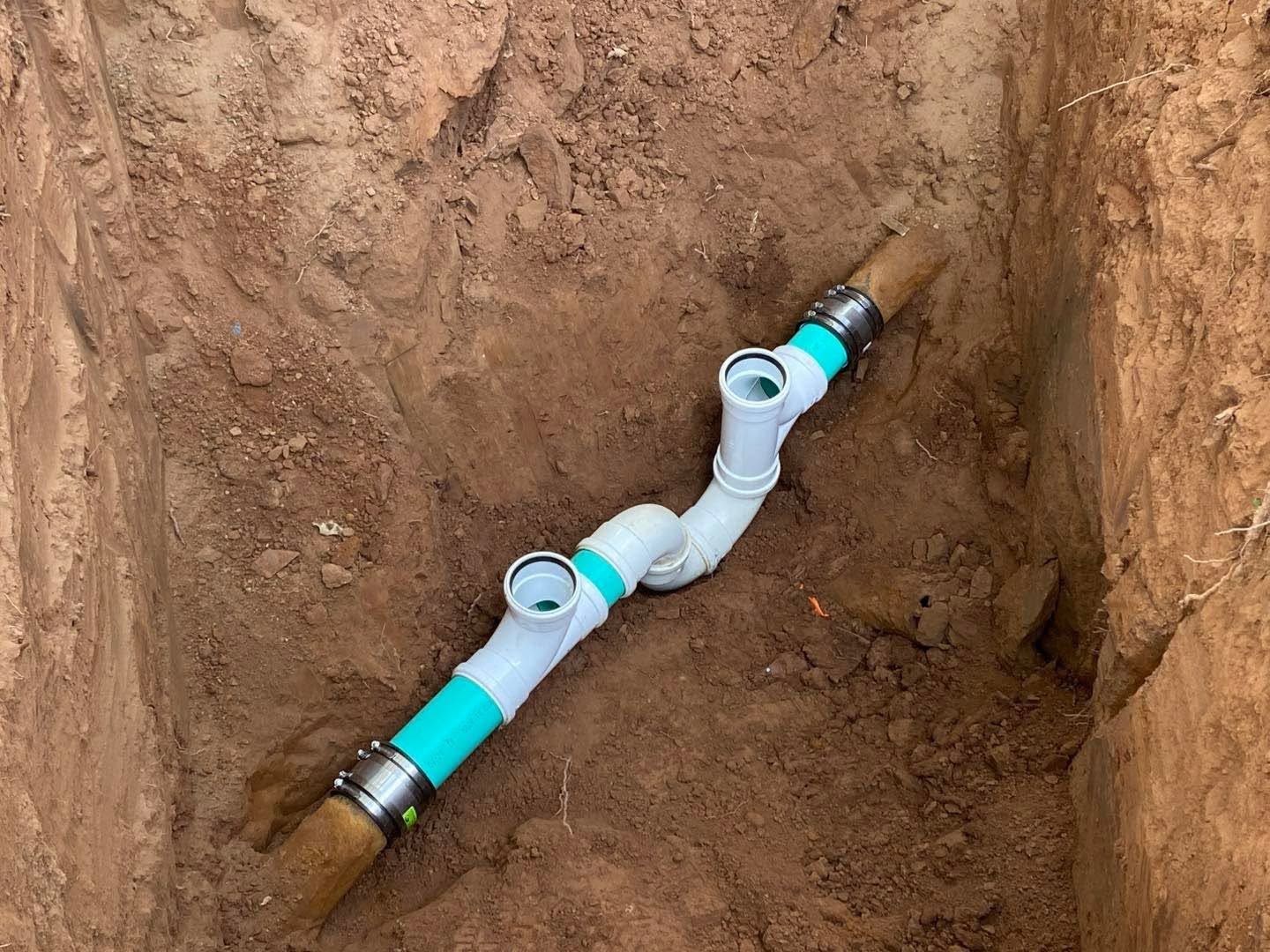 PVC pipe fitting laid in a dirt trench during underground plumbing installation