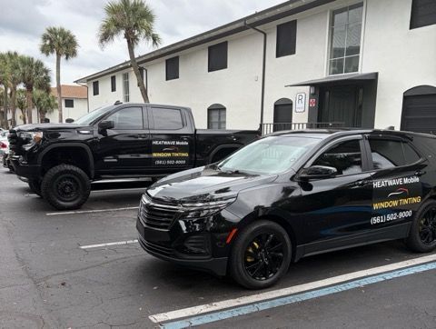 Two black vehicles parked in front of a building. Both vehicles have tinted windows and company logos.