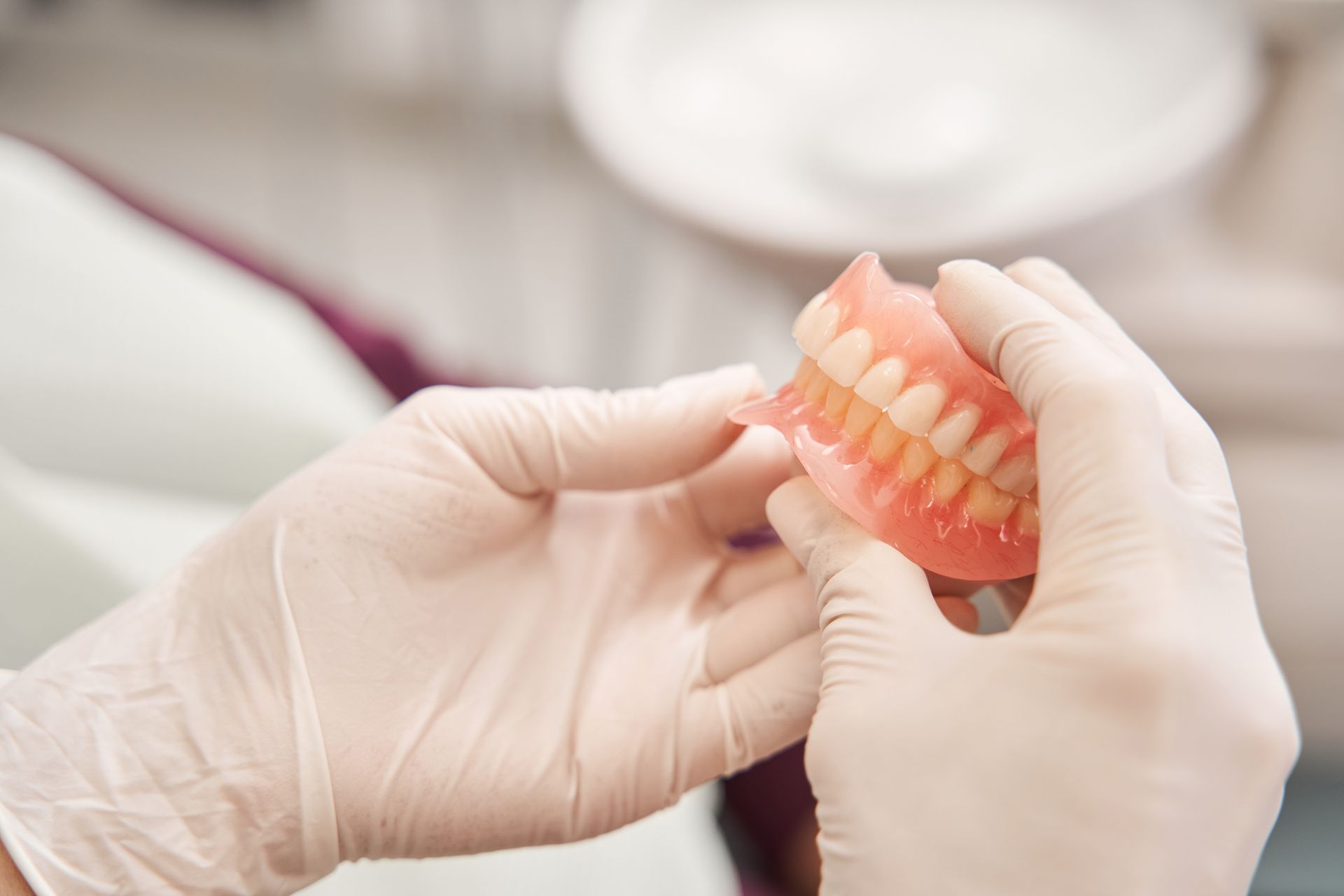 A dental prosthetist holding new dentures in their hands