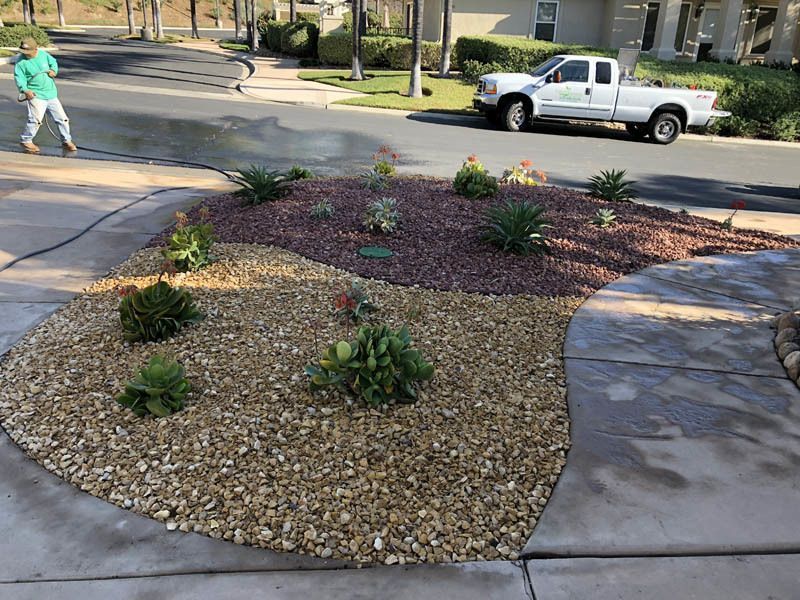 A white truck is parked in a driveway next to a garden