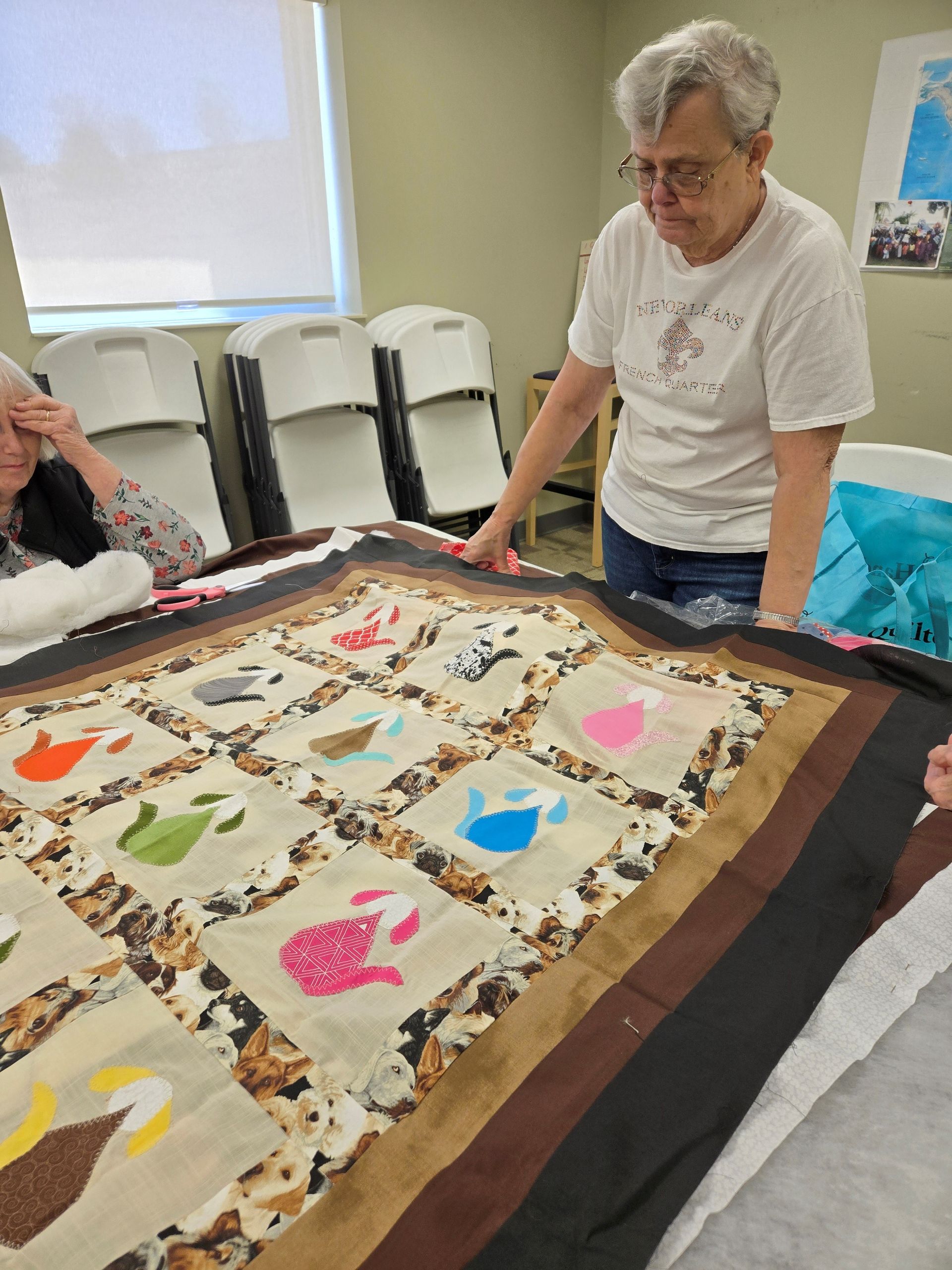 Woman examining a colorful quilt with other people in a well-lit room.