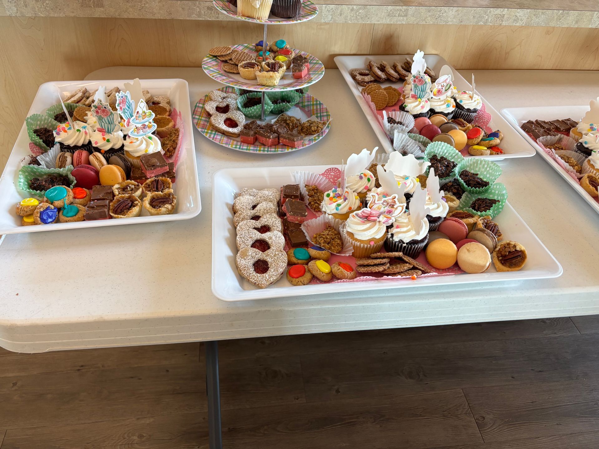 Dessert table with platters of assorted cookies, cupcakes, and pastries.