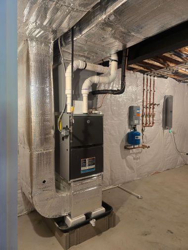 Utility room with a furnace, insulated ducts, and exposed plumbing in a basement-like space