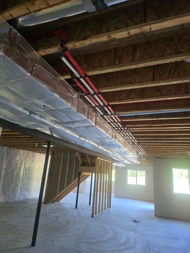 Unfinished basement with exposed beams, ductwork, and insulation in a construction site.