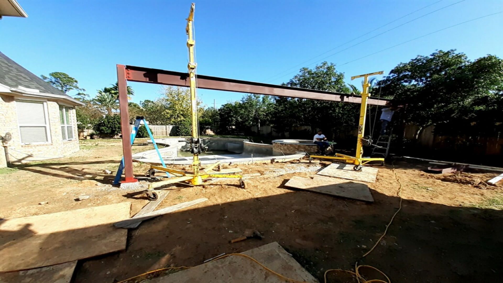 A large metal structure is being built in a backyard.