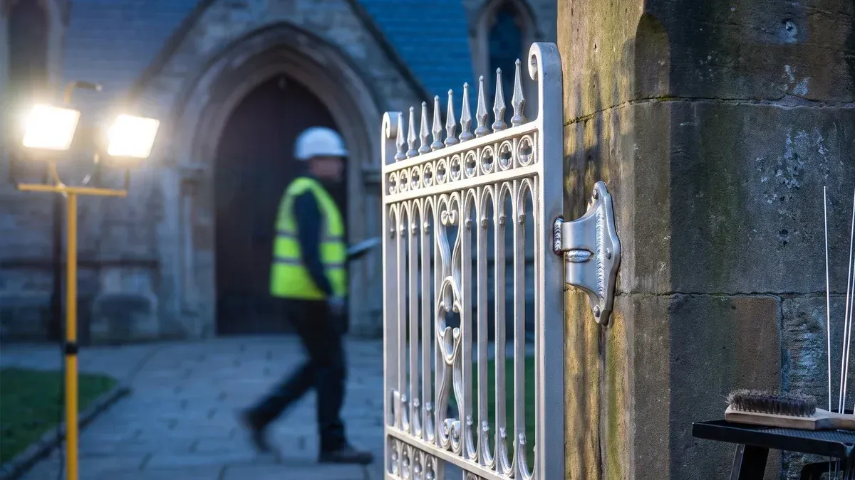 Cast aluminum church courtyard gate with a freshly welded hinge casting and repair tools nearby