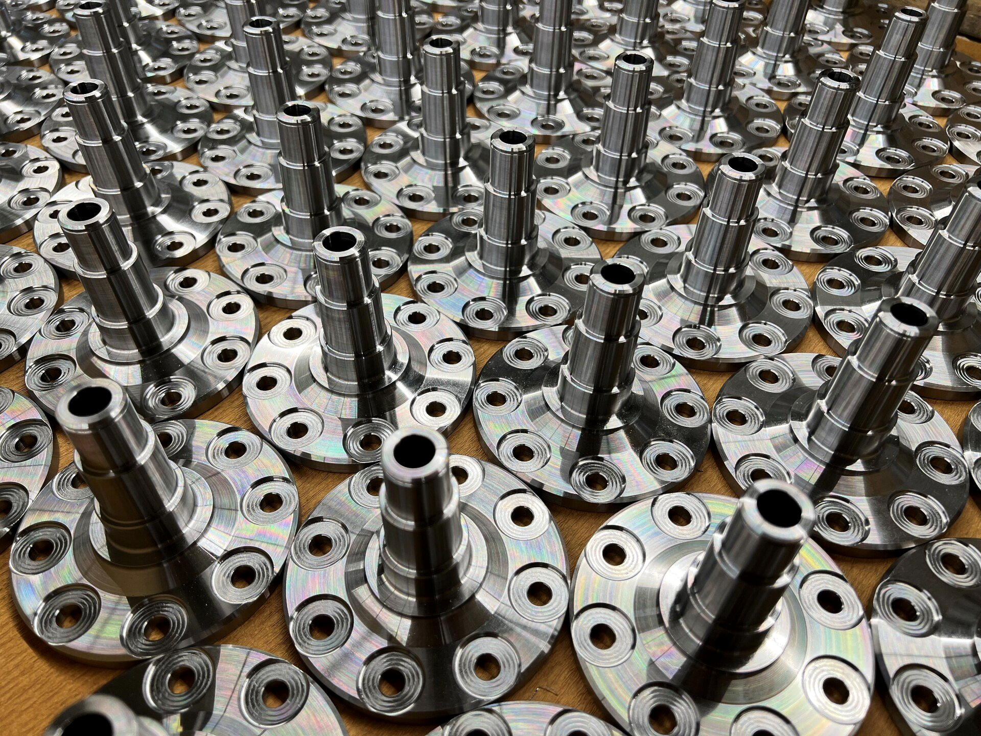 Zahlreiche bearbeitete Metallkomponenten mit zylindrischen Schäften und kreisförmigen Sockeln, ordentlich angeordnet.