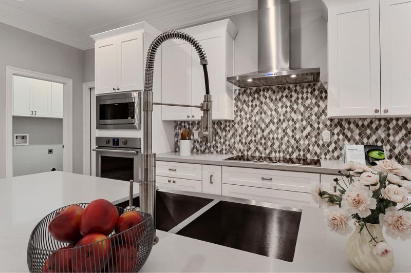 Modern kitchen with white cabinets, stainless steel appliances, and fruit on the counter.