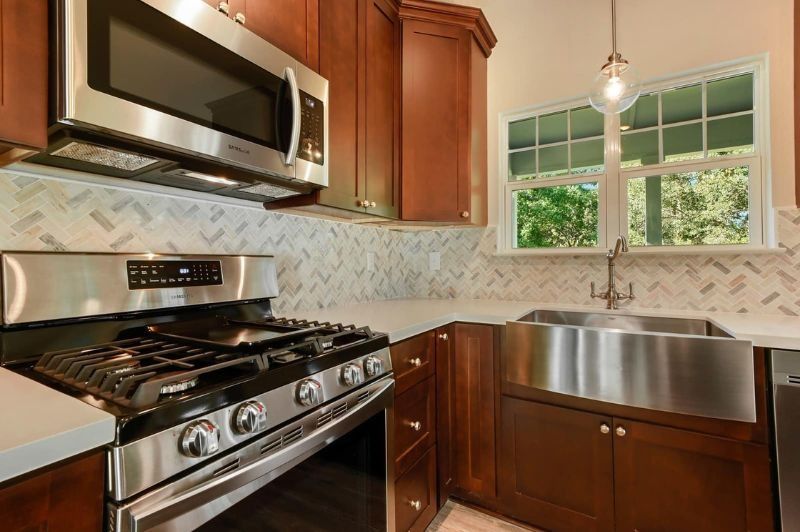 Stainless steel kitchen with dark wood cabinets, gas range, and farmhouse sink.