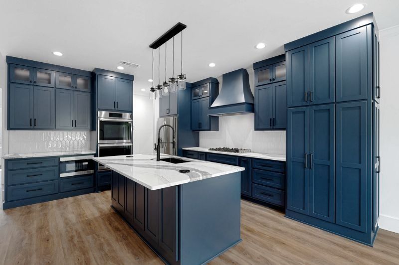 Navy blue kitchen with white countertops and a large island, modern design.