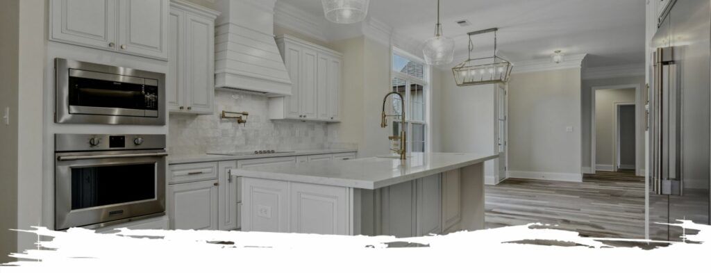 Modern white kitchen with a large island and stainless steel appliances.