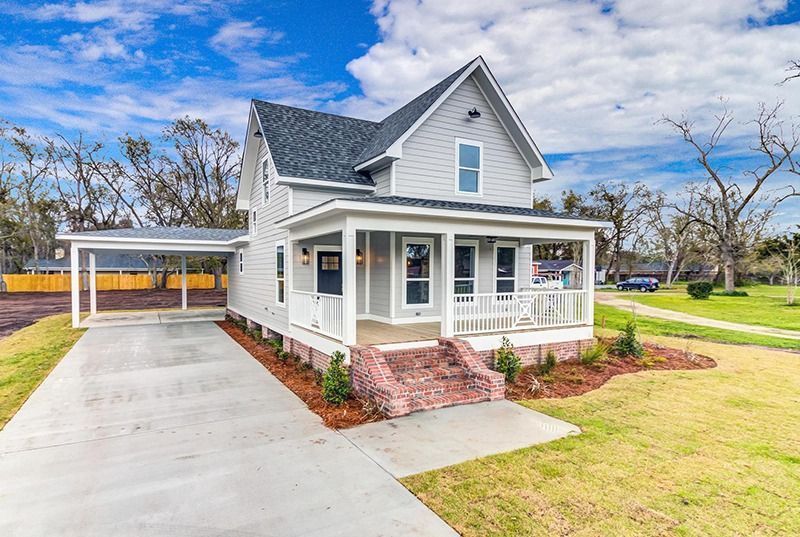 Gray two-story house with a porch and a carport. A green lawn in the front.