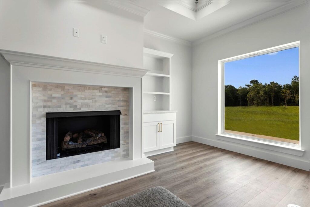 White fireplace with built-in shelving and a window overlooking a green field and trees.