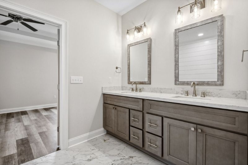Bathroom with double vanity, gray cabinets, marble countertops, and framed mirrors.