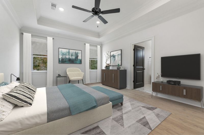 Spacious bedroom with a bed, TV, and a cabinet. The room has a neutral color palette and a ceiling fan.