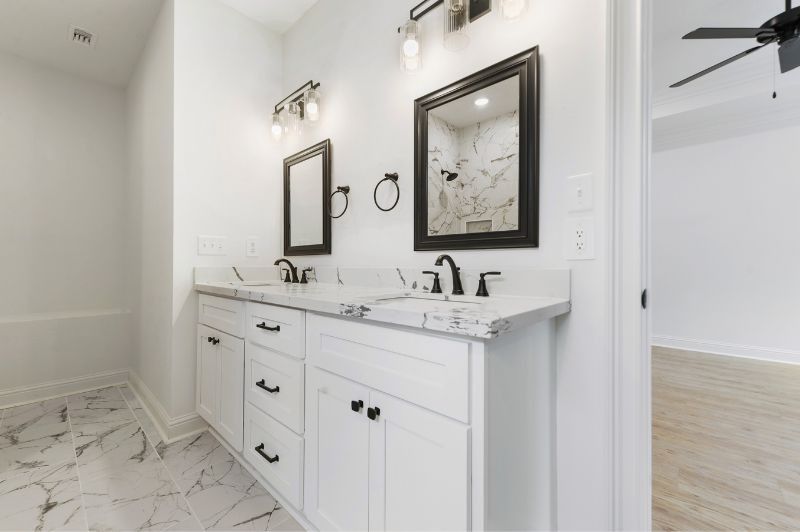 White bathroom with marble countertops, black accents, and dual sinks.