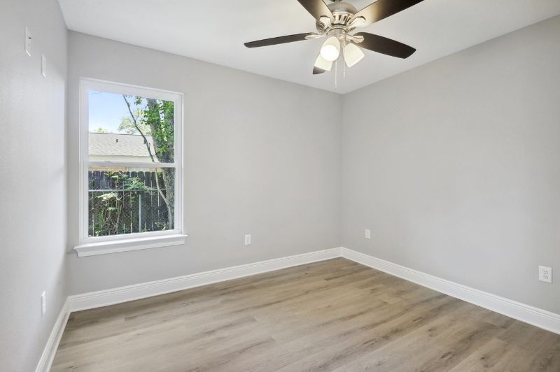 Empty bedroom with gray walls, wood-look floor, and window with outdoor view.