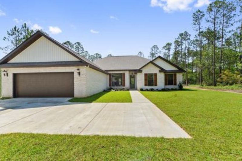 A single-story house with white brick exterior, brown garage door, and a concrete driveway.