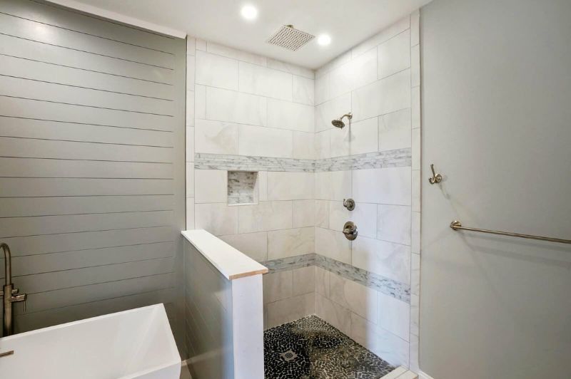 Bathroom with a tiled shower, shiplap wall, and a white bathtub; light gray and white color scheme.