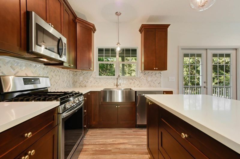 Kitchen with brown cabinets, white countertops, stainless steel appliances, and a view of the outdoors.