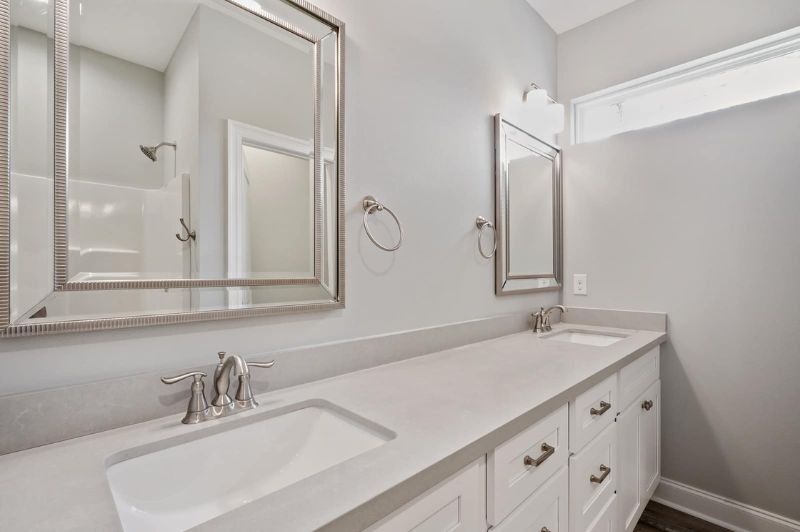 Bathroom with dual sinks, white vanity, large mirrors, and light gray walls.