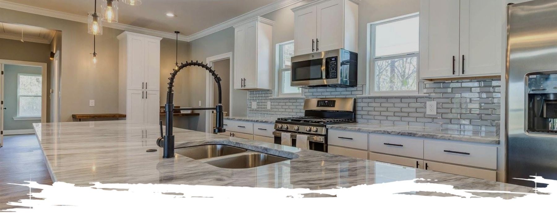 Modern kitchen with white cabinets, granite countertops, stainless steel appliances, and black faucet.
