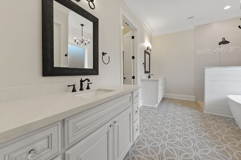Bathroom with white cabinets, black fixtures, patterned floor, and a shower.