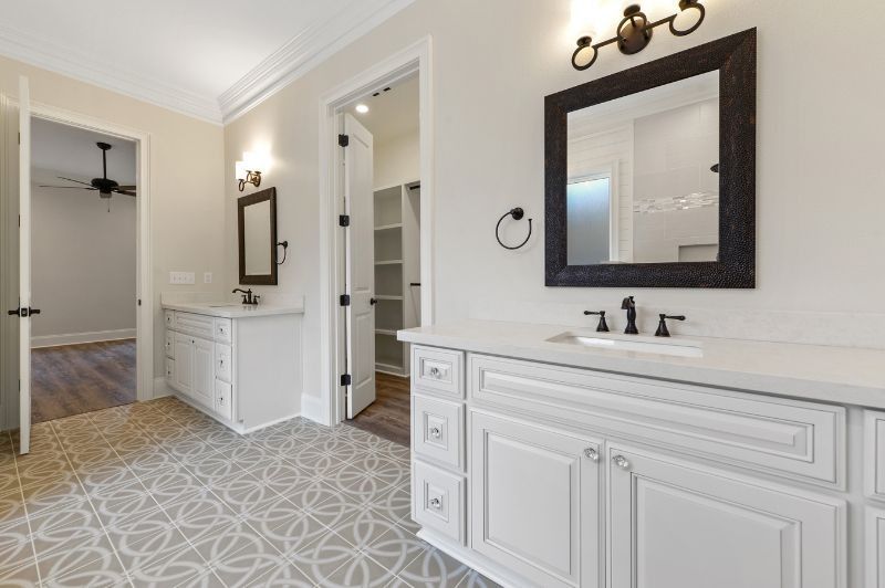 Bathroom with white cabinets, patterned floor, dark-framed mirrors, and open closet.