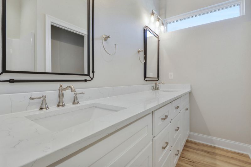 White bathroom vanity with two sinks, framed mirrors, and brushed nickel hardware.