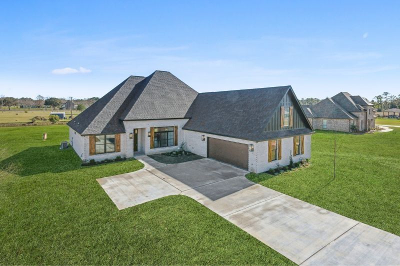 Modern, single-story house with grey roof and tan brick facade; set on a grassy lawn.