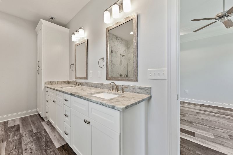 White bathroom with double sinks, mirrors, and a tall storage cabinet.